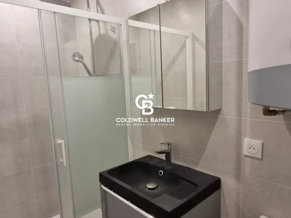 Salle de bain moderne avec douche, lavabo et toilettes dans un appartement rénové.