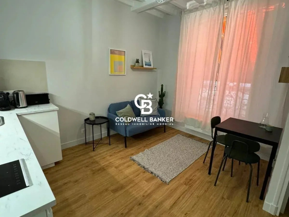 Intérieur d'un studio rénové avec coin cuisine, table et chaises, et lumière naturelle.
