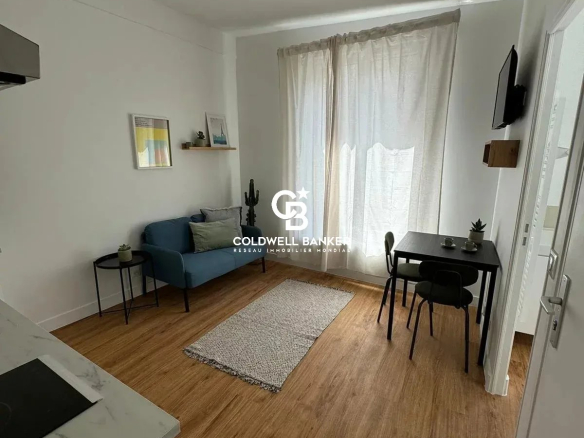 Intérieur d'un studio rénové avec salon, table et chaises, éclairage naturel.