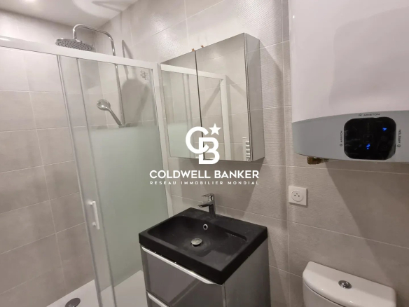 Salle de bain moderne avec douche, lavabo et toilettes dans un appartement rénové.