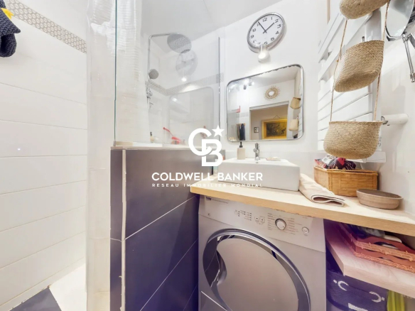 Salle de bain d'un appartement avec lavabo, machine à laver et miroir.
