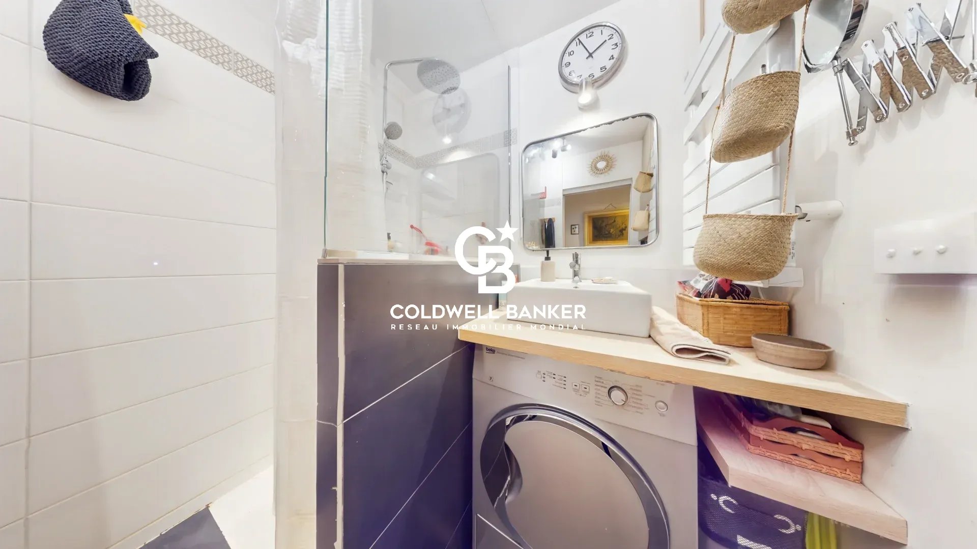 Salle de bain d’un appartement à Montrouge Salle de bain d'un appartement avec lavabo, machine à laver et miroir.