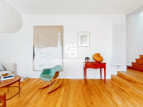 Intérieur d'une maison moderne avec un salon lumineux et un escalier en bois.