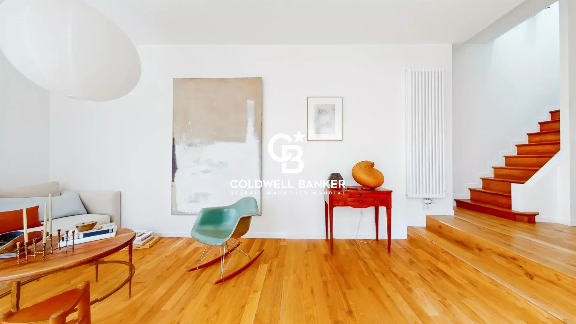 Intérieur d'une maison moderne avec un salon lumineux et un escalier en bois.