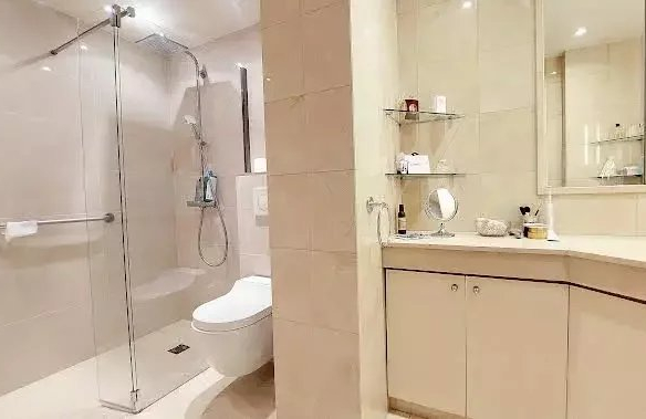 Modern bathroom with a glass-enclosed shower, wall-hung toilet, and beige vanity with a mirror above it.