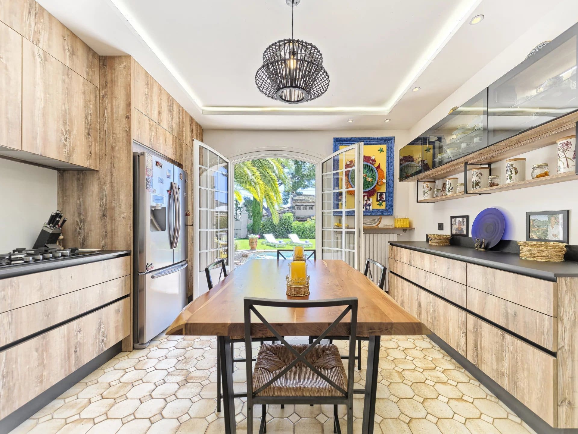 Modern kitchen with wooden table and view of the garden and pool.