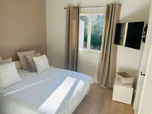 Chambre d'une villa à Mougins avec lit double, télévision et fenêtre donnant sur l'extérieur.