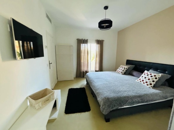 Chambre d'une villa à Mougins avec lit double, télévision et fenêtres donnant sur l'extérieur.
