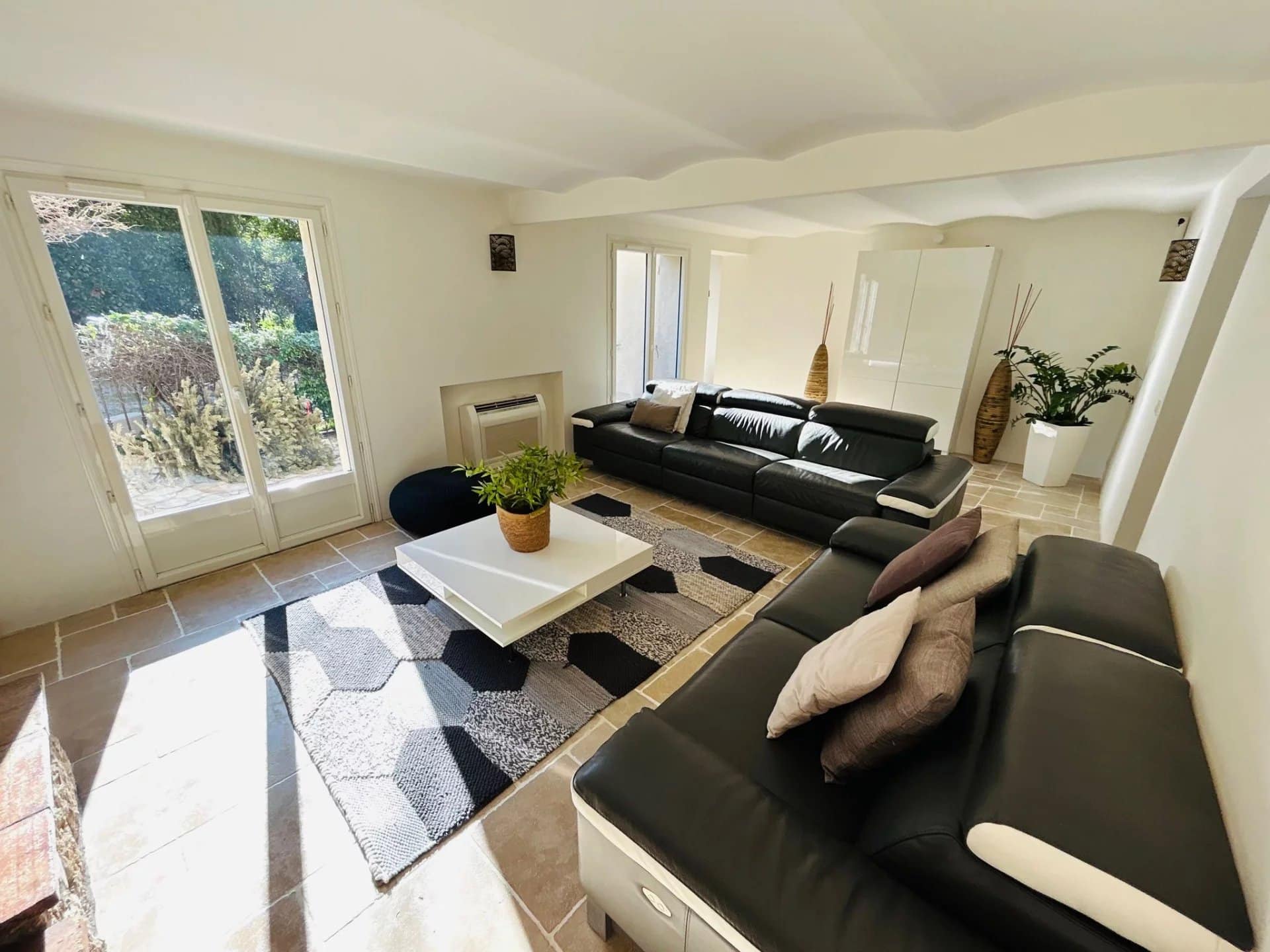 Intérieur d'une villa à Mougins avec un salon moderne et lumineux, canapé noir et décoration sobre.