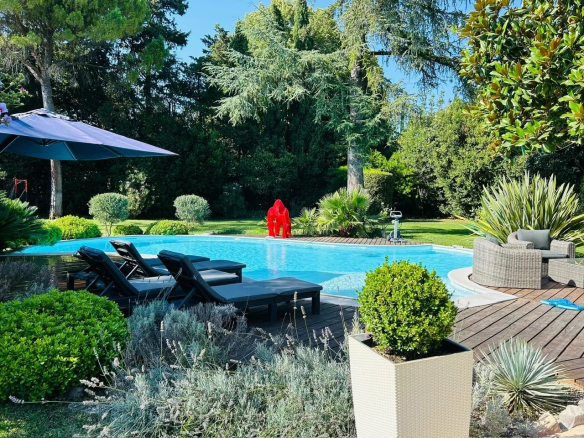 Vue d'une villa avec piscine, transats et jardin paysagé à Mougins.