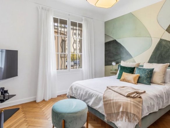 Chambre d'un appartement à Cannes avec un lit, un téléviseur et des décorations murales modernes.