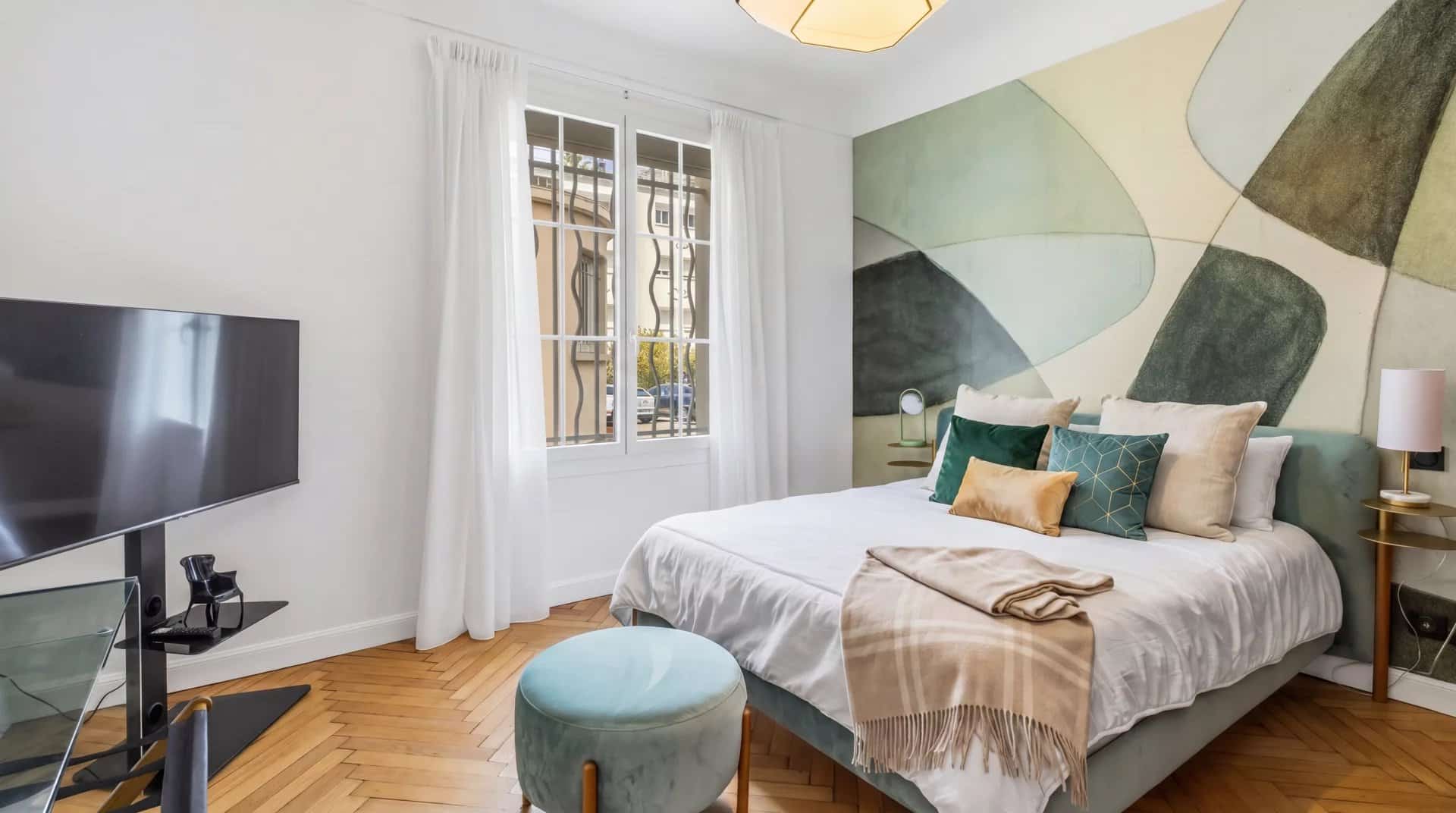 Chambre d'un appartement à Cannes avec un lit, un téléviseur et des décorations murales modernes.