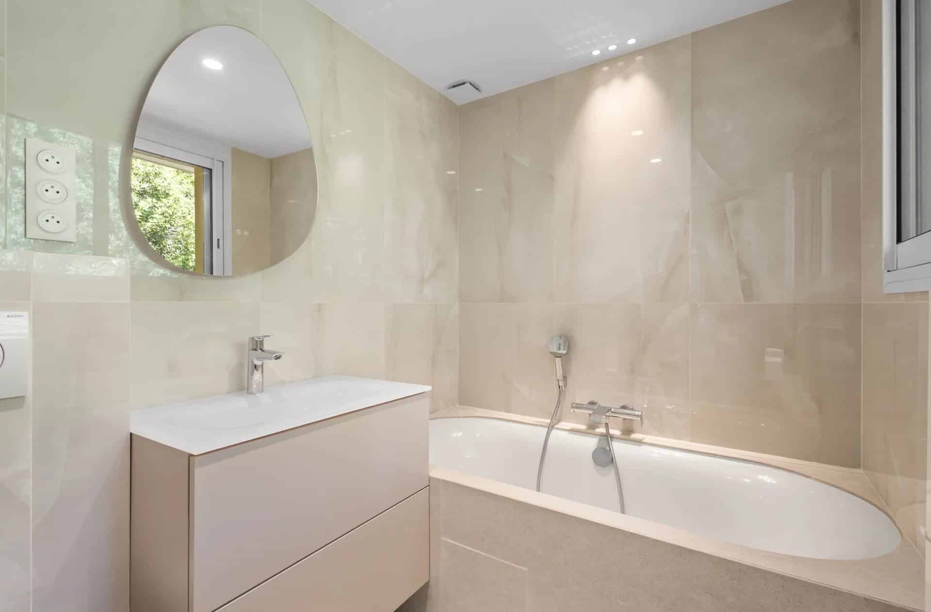 Salle de bain moderne avec baignoire et lavabo dans un appartement rénové.