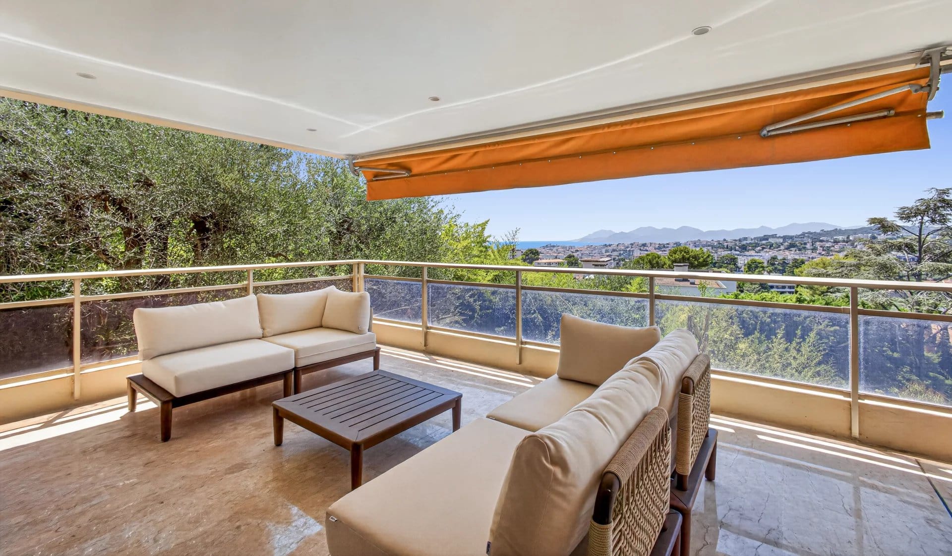 Terrasse d'un appartement à Le Cannet avec vue sur la mer et les collines, mobilier d'extérieur confortable.