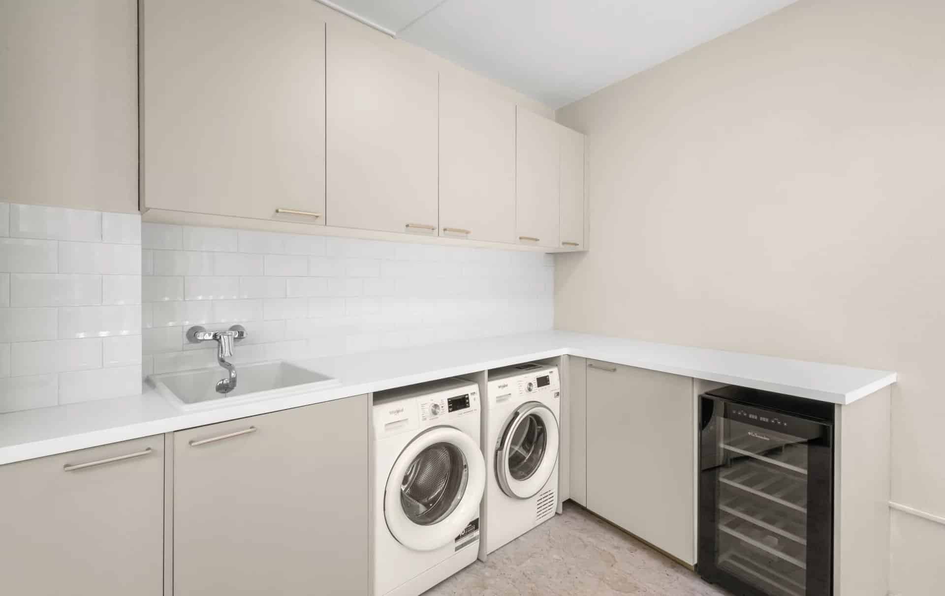 Cuisine moderne avec lave-linge et réfrigérateur dans un appartement rénové.