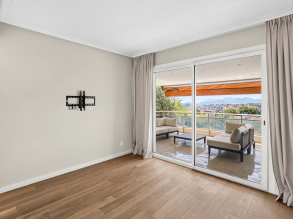 Intérieur d'un appartement rénové avec sol en bois et grandes baies vitrées donnant sur une terrasse avec vue mer.