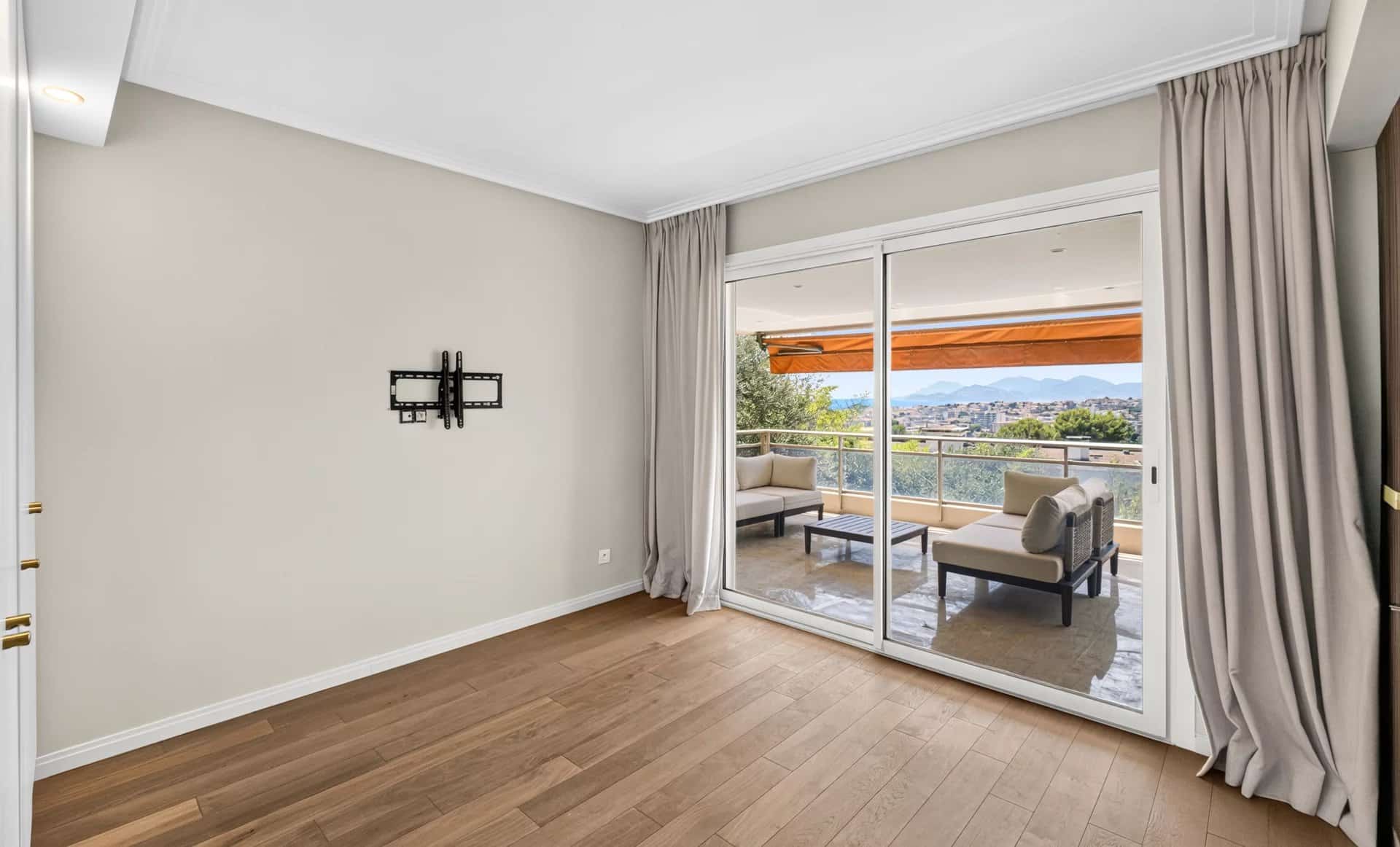 Intérieur d'un appartement rénové avec sol en bois et grandes baies vitrées donnant sur une terrasse avec vue mer.
