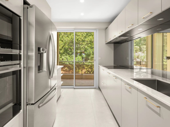 Cuisine moderne d'un appartement rénové avec vue sur la terrasse et le jardin.