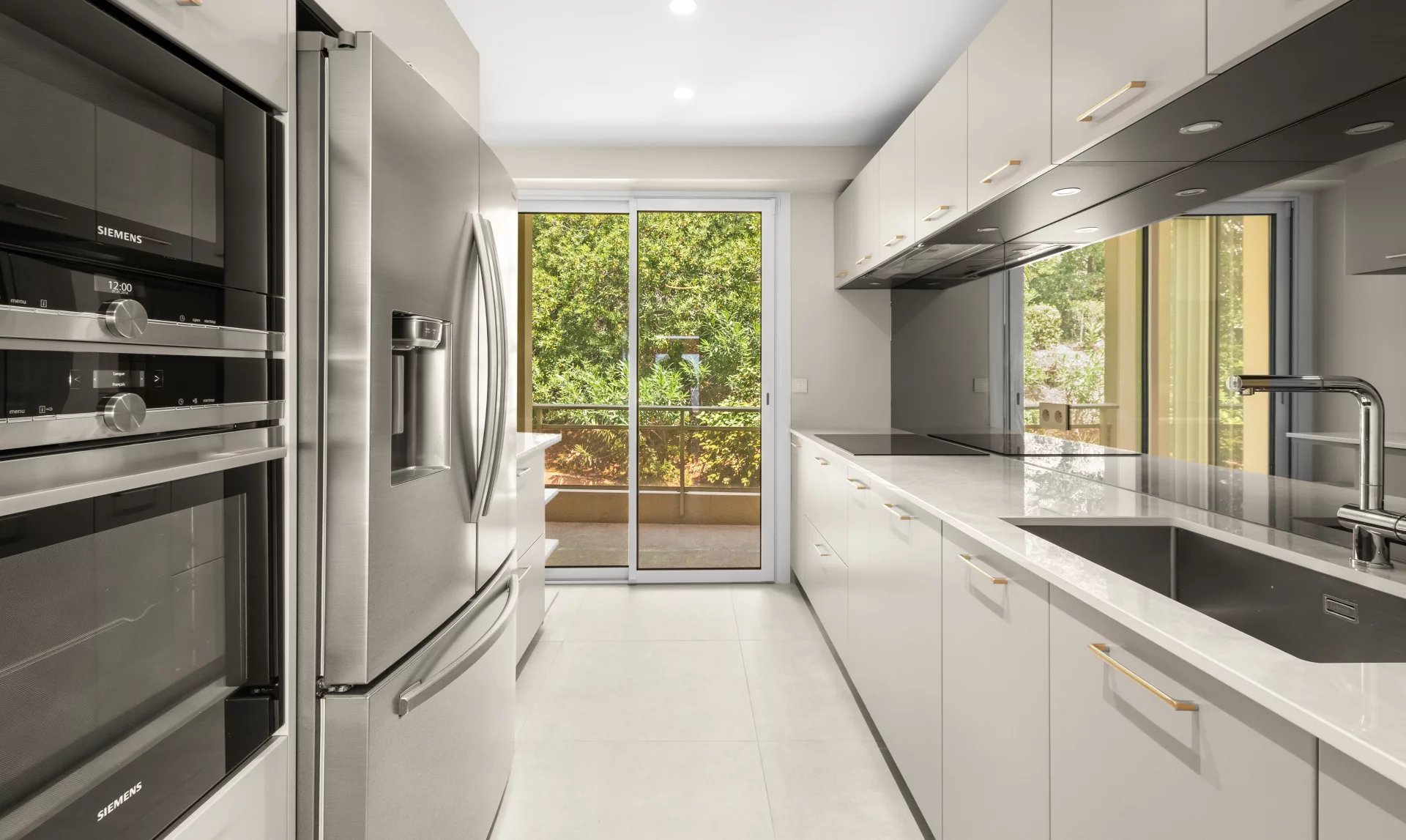 Cuisine moderne d'un appartement rénové avec vue sur la terrasse et le jardin.