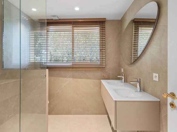 Salle de bain moderne avec douche en verre et double vasque, éclairage naturel.