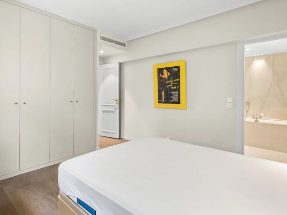 Chambre d'un appartement rénové avec placards intégrés et salle de bain attenante.