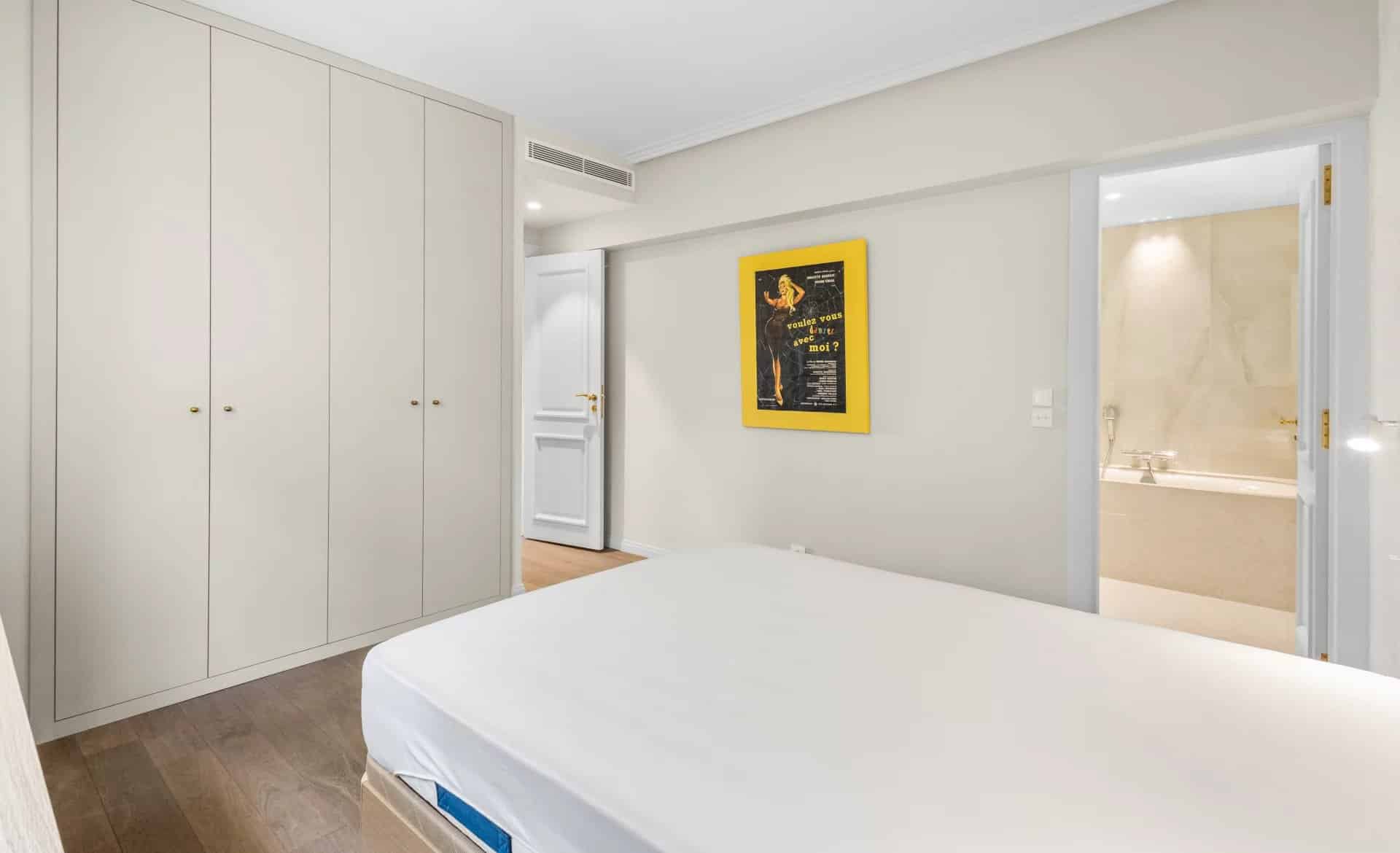 Chambre d'un appartement rénové avec placards intégrés et salle de bain attenante.
