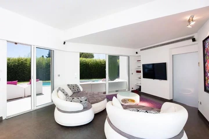 Interior of a detached villa in Mougins with a modern living room and a view of the swimming pool.