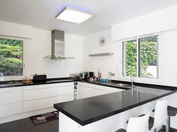 Modern and bright kitchen of a detached villa in Mougins, with black worktops and windows.