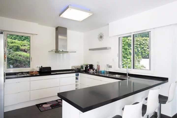 Modern and bright kitchen of a detached villa in Mougins, with black worktops and windows.
