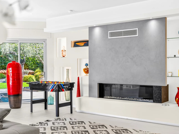 Intérieur d'une villa moderne avec un salon lumineux, cheminée et table de jeux.