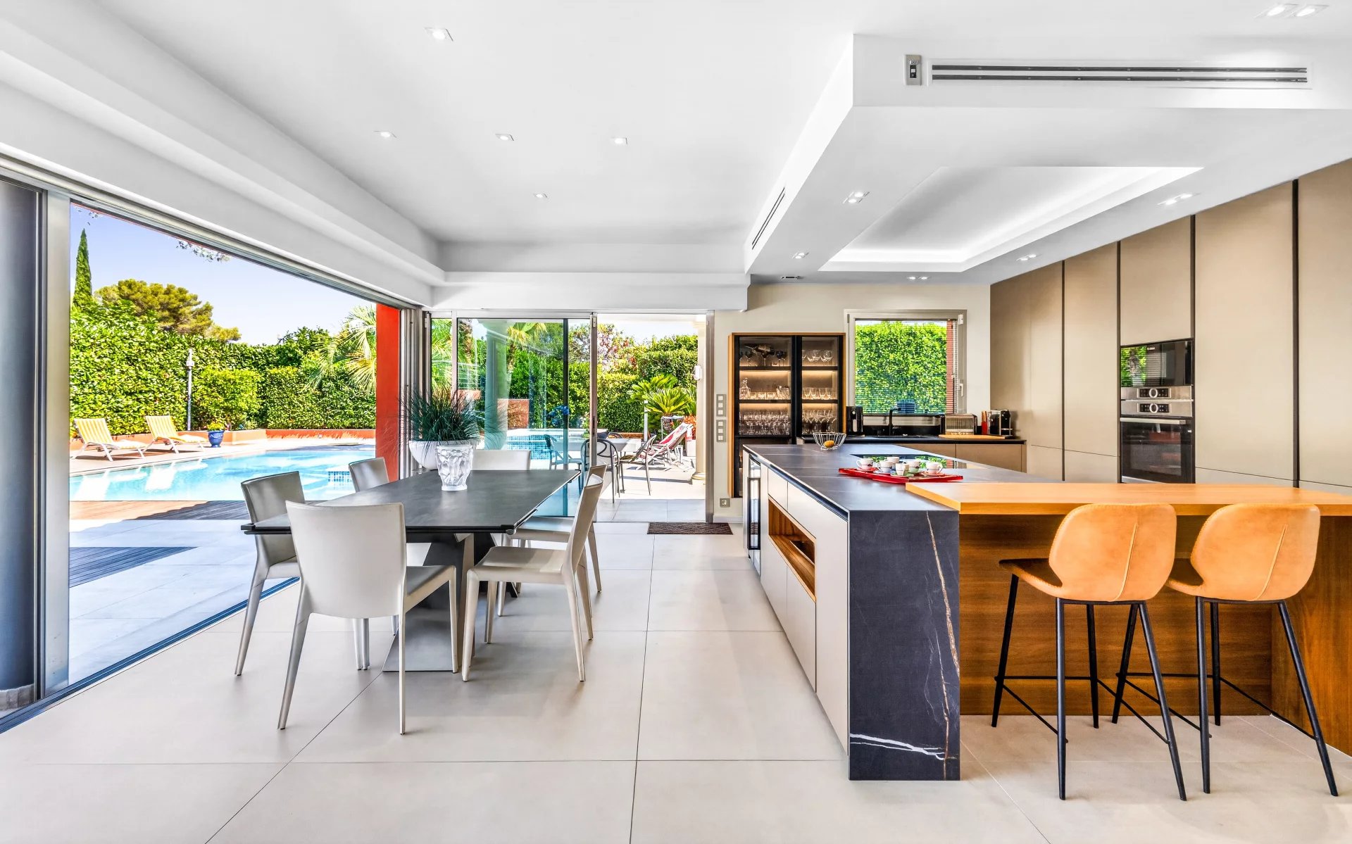 Intérieur d’une villa à Mougins Intérieur d'une villa moderne avec cuisine équipée et salle à manger, vue sur la piscine extérieure.