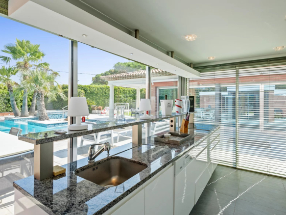 Intérieur d'une villa moderne avec cuisine équipée et vue sur la piscine extérieure