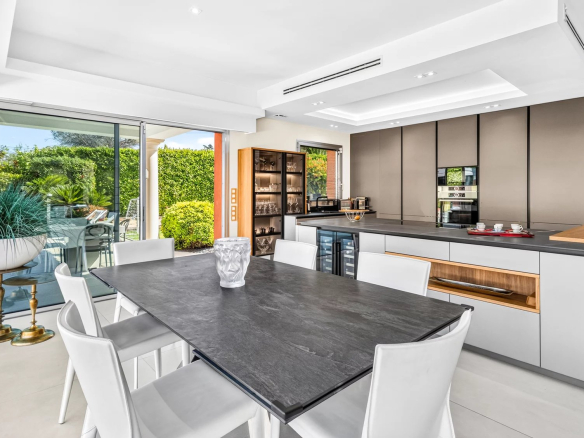 Cuisine moderne et lumineuse avec salle à manger, ouvrant sur l'extérieur et la piscine.