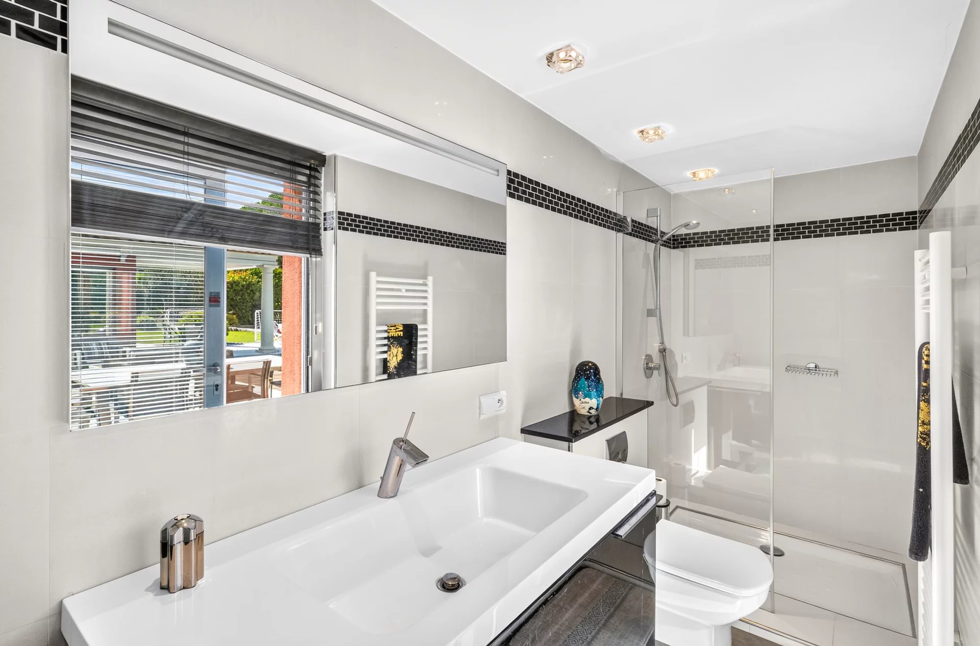 Salle de bain de la villa à Mougins Salle de bain moderne avec douche et lavabo, vue sur l'extérieur avec piscine