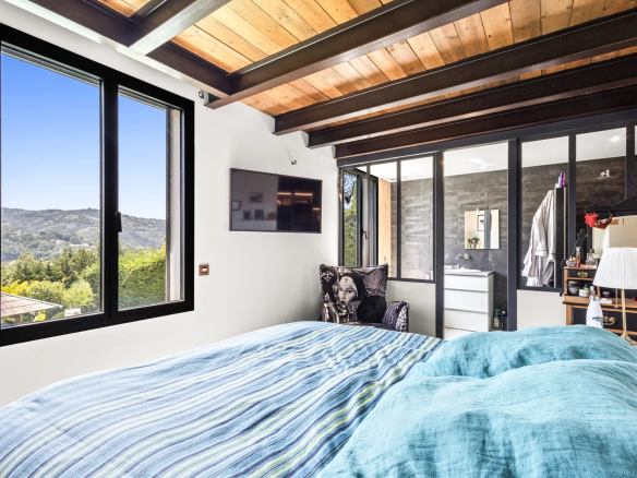 Room in a modern villa with nature view, bed and wall-mounted television.