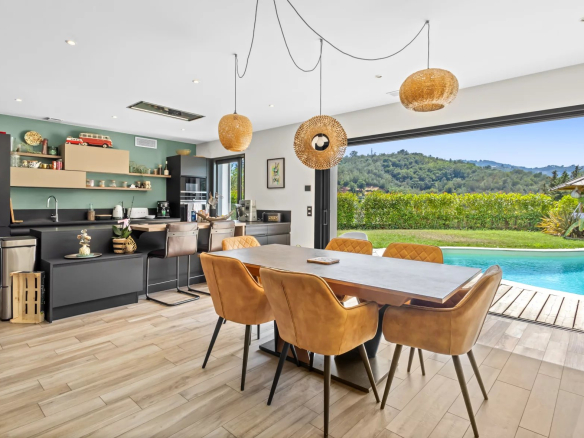 Interior of a modern villa with fitted kitchen and dining room, overlooking the pool and garden.