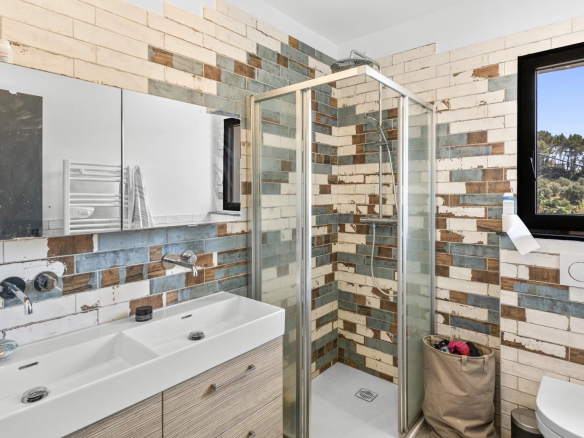 Modern bathroom with glass shower and mosaic tiles.