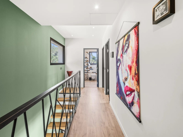 Interior of a modern villa with a bright hallway and a colorful piece of art on the wall.