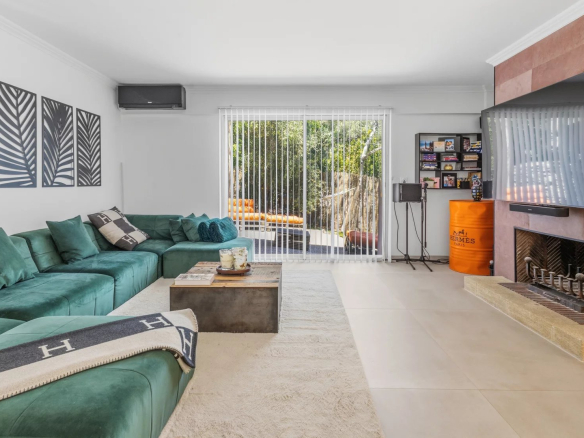 Intérieur d'une villa moderne avec un salon spacieux et lumineux, canapé vert et cheminée.
