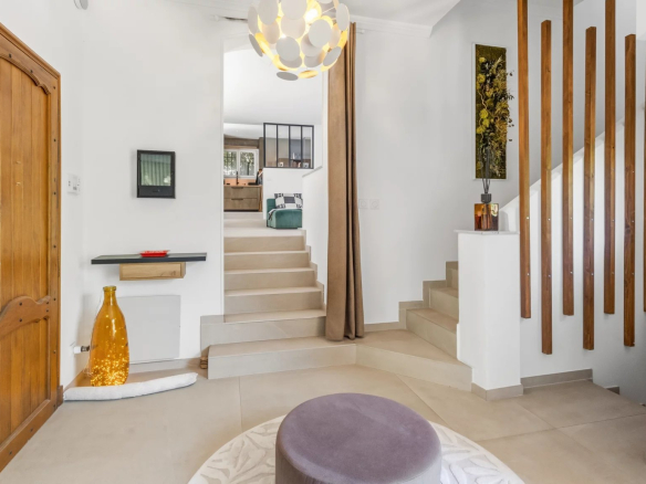 Intérieur d'une villa moderne avec un hall d'entrée lumineux et un escalier menant à l'étage.