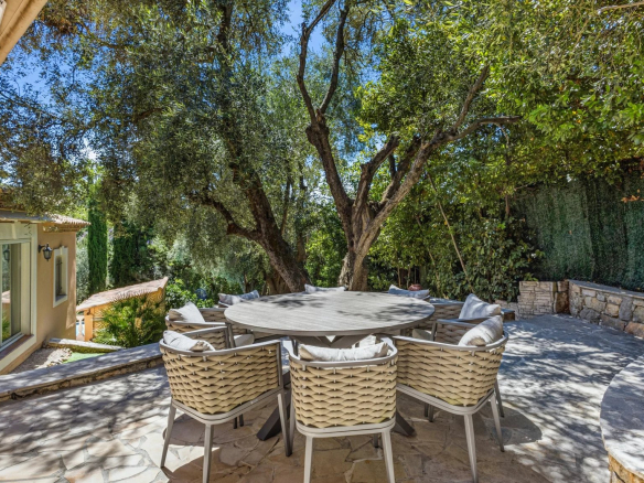 Terrasse avec table et chaises entourée d'arbres dans une villa au Cannet.