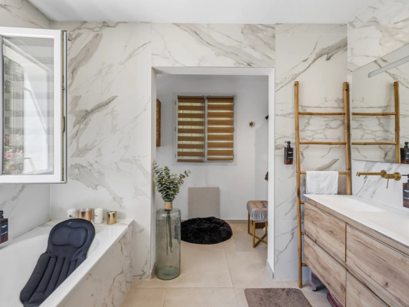 Salle de bain moderne avec baignoire et meuble en bois, décorée de marbre.