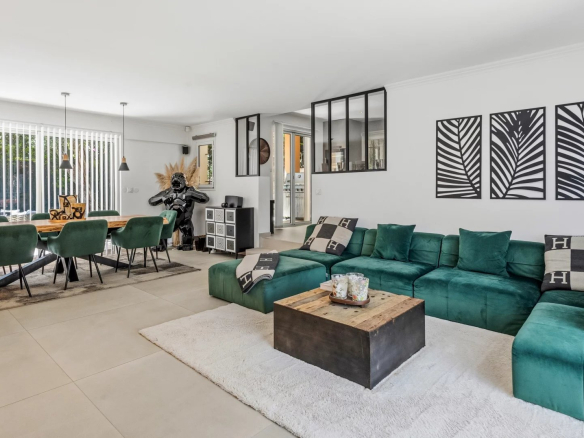 Intérieur d'une villa moderne avec salon et salle à manger, décoré de canapés verts et d'une table en bois.
