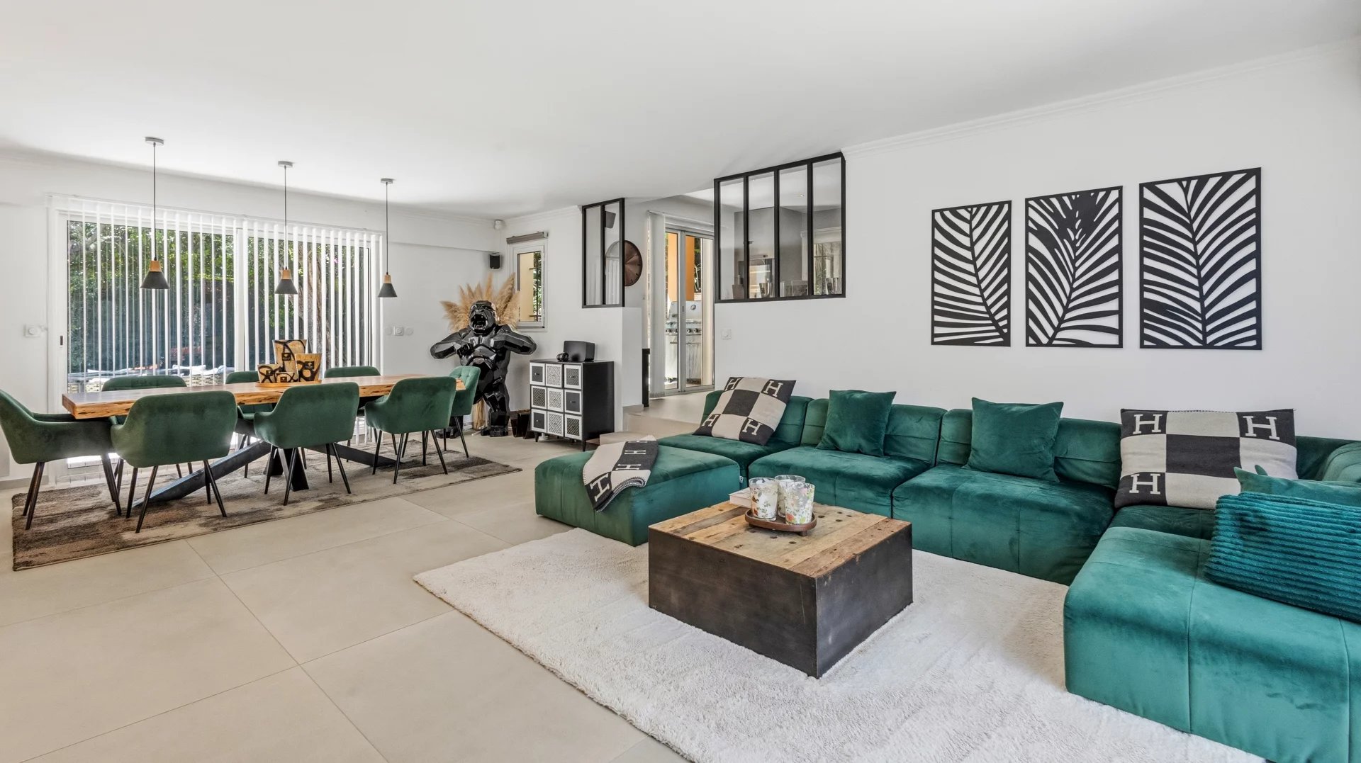 Intérieur d’une villa au Cannet Intérieur d'une villa moderne avec salon et salle à manger, décoré de canapés verts et d'une table en bois.