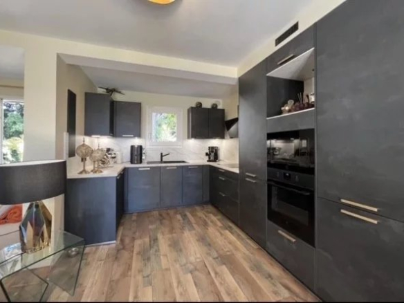 Modern and fully equipped kitchen in a villa in Cannes, with wooden furniture and integrated appliances.