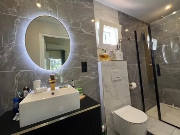 Modern bathroom with walk-in shower and sink, decorated with marble tiles.