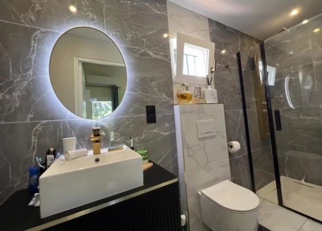Modern bathroom with walk-in shower and sink, decorated with marble tiles.