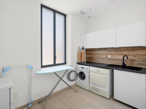 Modern laundry room with washing machines and ironing board in a renovated villa in Cannes.