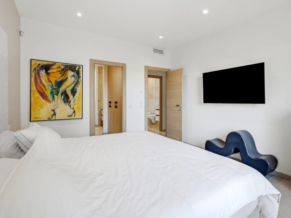 Room in a renovated villa with bed, painting and wall-mounted television.