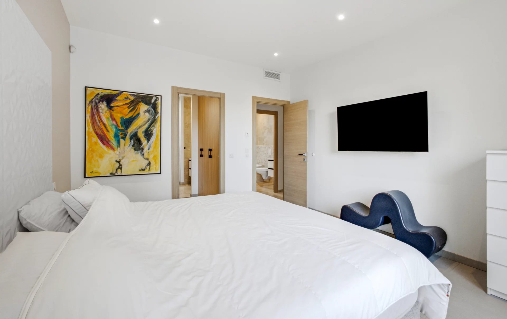 Villa room at Petit Juas Room in a renovated villa with bed, painting and wall-mounted television.